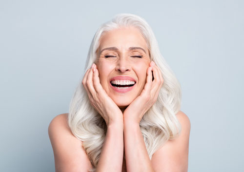 elderly lady touching cheeks laughing