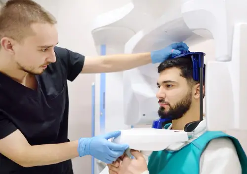 Medical professional positioning a patient for a digital panoramic X-ray scan in a clinical setting.