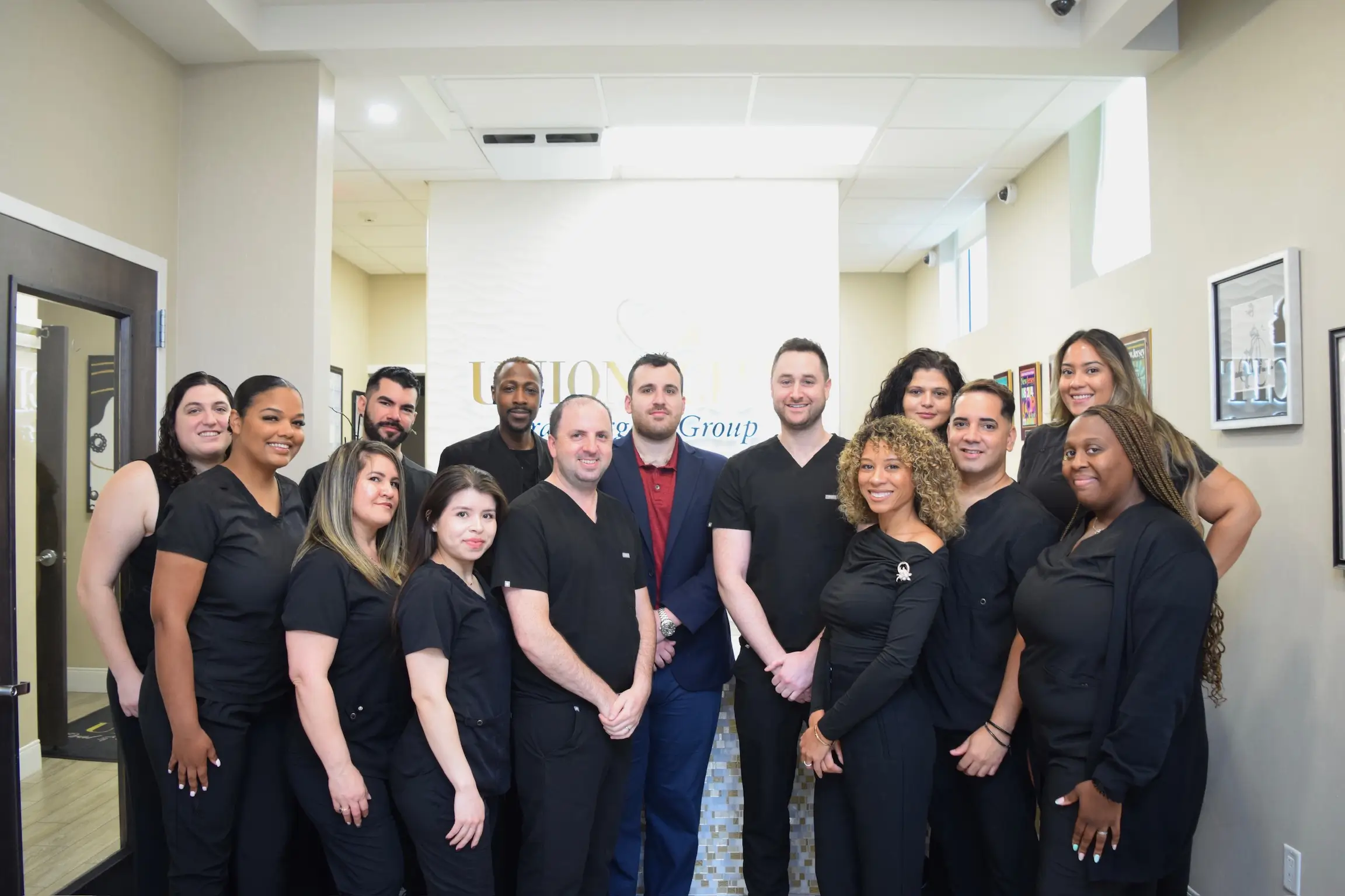 Group of diverse dental professionals in black scrubs and business attire standing in a clinic lobby