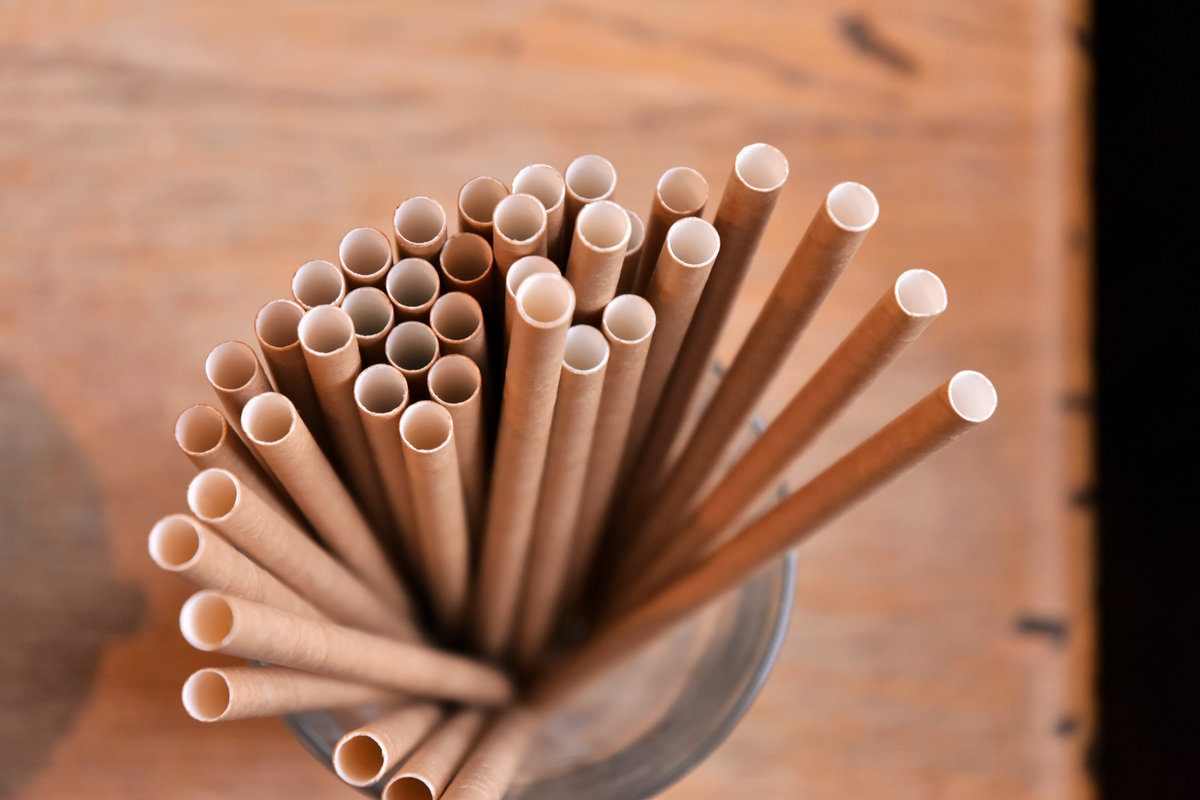Eco friendly Reusable Straws in the cardboard cup with selective focus and blurred ba. Paper cocktail tubes. Kraft paper straw for drinking coffee or tea. Disposable cocktail tube.
