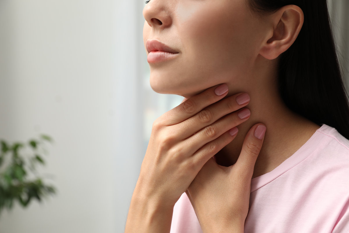 Young woman doing thyroid self examination indoors, closeup. Space for text
