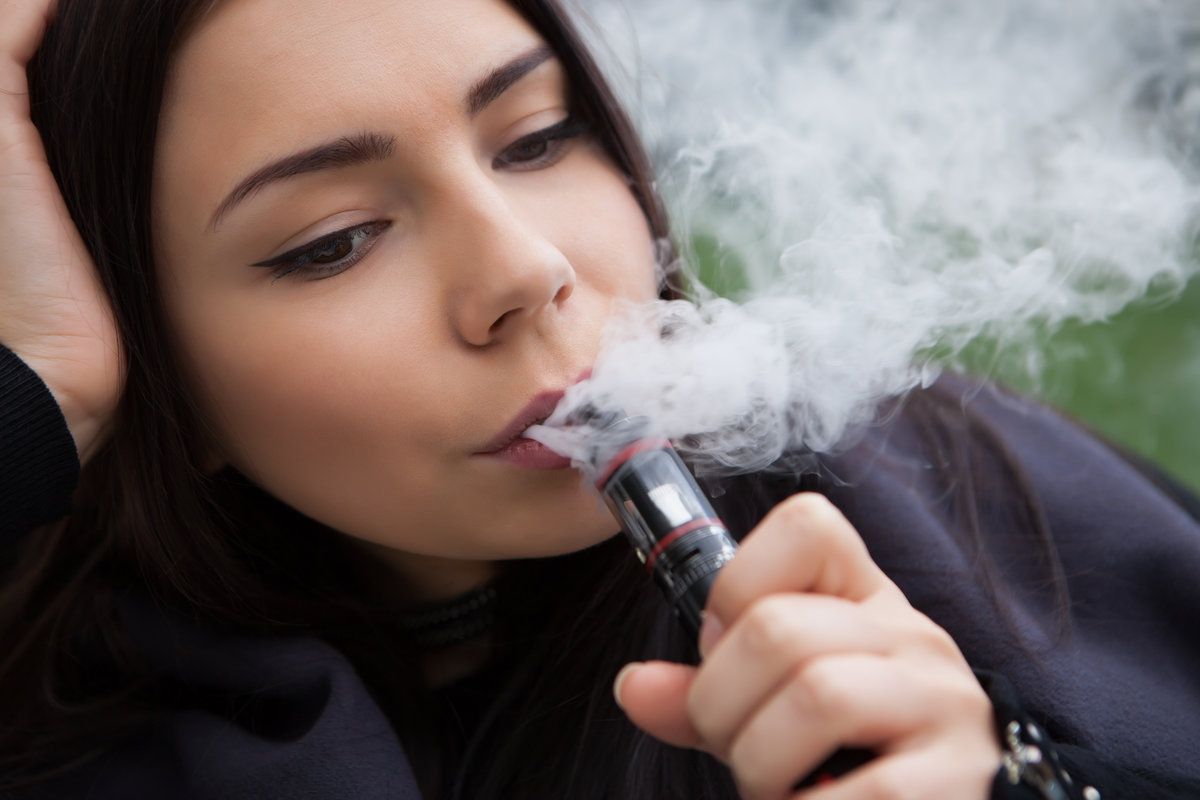Pretty young girl smoking electronic cigarette
